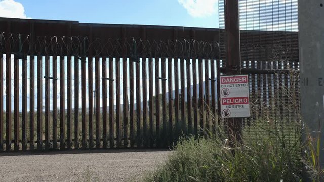Border fence along Mexico with razor wire and danger sign