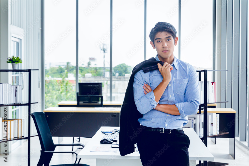 Wall mural Young Asian Businessperson is standing smart poses and smile at co working space decorated in modern office style for startup business students and freelancers