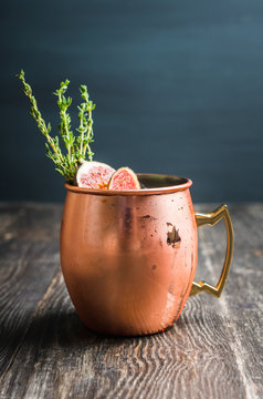 Moscow mule cocktail with figs and thyme on the rustic background. Selective focus. Shallow depth of field.