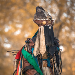 Mongolian traditional shaman performing a traditional shamanistic ritual with a drum and smoke in a...