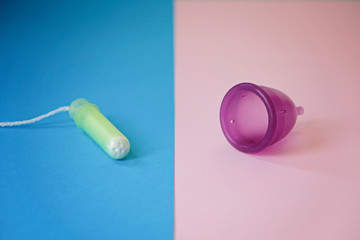 Menstrual cup and tampon on pink and blue background, concept of women's health and ecology of the planet