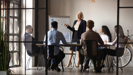 Mature businesswoman mentor coach give flip chart presentation at workshop