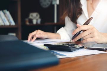 Woman using calculator at office desk.