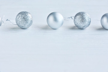 Shiny Christmas balls with selective focus on a neutral wooden background. Christmas and New Year flat lay. New Year 2020 flat lay with silver decorative ball on white textured background, soft focus 