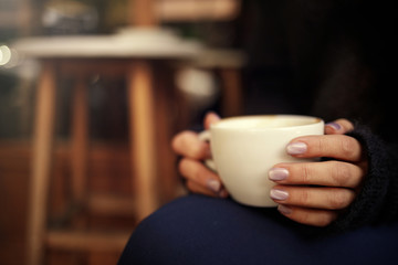 Female hand hold hot coffee cup in cafe
