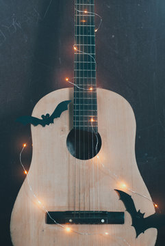 Acoustic guitar in autumn season. guitar with garland and bat. Concept sale of guitars on Halloween and black Friday,