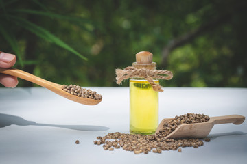 Hemp seeds in wooden spoon and hemp essential oil in small glass bottle. cannabis oil cbd.