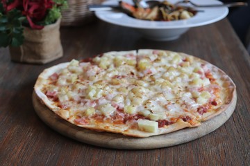 Hawaiian pizza in wooden tray on the table