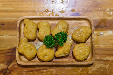 A pile of chicken nuggets on wooden plate