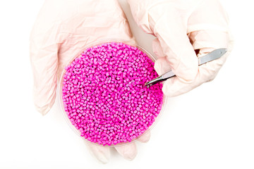 Plastic pellets . Colorant for polymers in granules. Worker wearing gloves takes plastic pellets with tweezers.