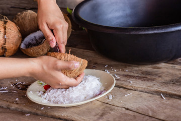 Woman using hand scraping coconut put the container for make dessert and food. Select Focus