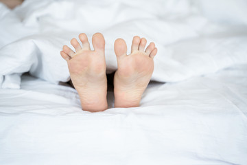 Obraz na płótnie Canvas Caucasian young woman feet lying in bed