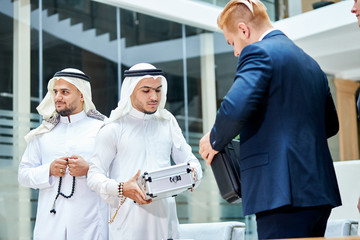 Obraz premium Arabic businessman give money for barter, buy new technology by caucasians