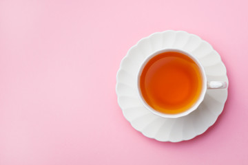 Tea in white cup on pink background. Copy space. Top view.