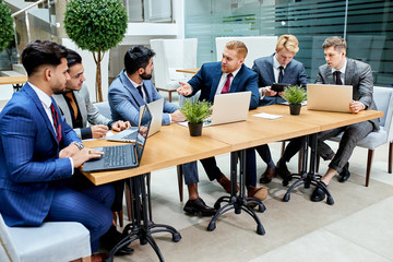 International meeting of businessmen. Multi-ethnic group of arabic and american negotiators, sitting on table