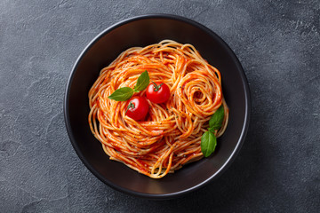 Pasta, spaghetti with tomato sauce in black bowl. Slate background. Top view.