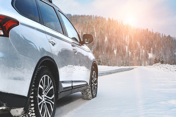 Modern Suv four wheel drive car stay on roadside of winter road. Family trip to ski resort concept. Winter or spring holidays adventure. car on winter snowy road in mountains in sunny day. - Powered by Adobe
