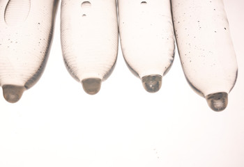 Closeup of condoms filled with water, on a white background.