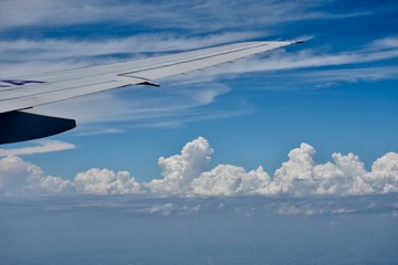 Beautiful white clouds in a blue sky and wing of an airplane
