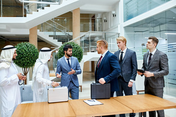Translator between businessmen, sheikh and caucasian. Sheikh holding white case, caucasian black...