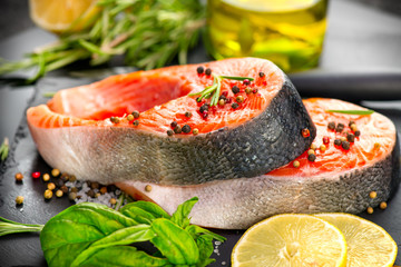 Salmon. Raw Trout Red Fish Steak served with Herbs, Lemon and olive oil on slate. Cooking Salmon, sea food. Healthy eating concept, Mediterranean cuisine 