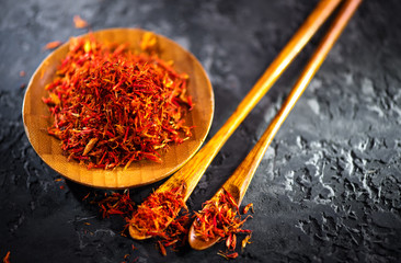 Saffron Spice. Saffron spices on black stone table in a wood bowl and a spoon. Spice and herbs on...