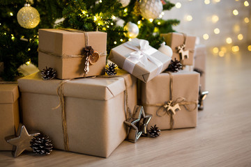 close up of beige gift boxes near decorated christmas tree