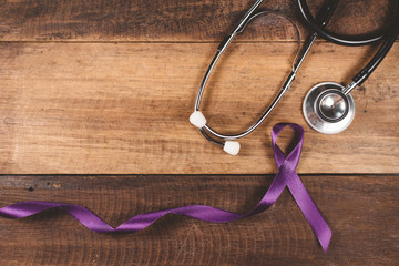 Purple ribbon and stethoscope on a wooden table. Concept of EPILEPSY awareness and medical treatment