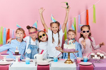crazy little boys and girls celebrating special event, isolated pink background, studio shot