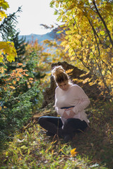 Young pregnant woman in nature enjoying autumn sun outdoors.