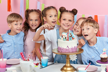 children waiting the process of cutting birthday cake, isolated pink background studio shot