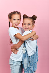 cute two friends hugging in the studio with pink wall, close up photo. isolated pink background, happy childhood , close up photo