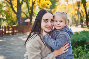 Happy family on autumn walk. Mother and daughter walking in Park and enjoying beautiful autumn nature. Hello, Autumn! Happy loving family having fun. Autumn leaf fall