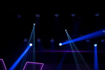 Light beams on stage with blue, green, red and pink from music festival. Rays of searchlights looks very strong against the darkness as a background.