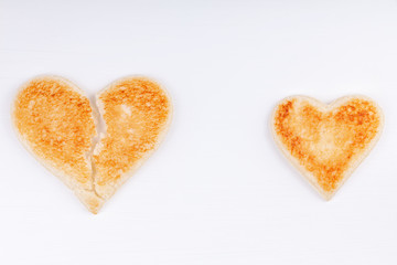 Bread toast broken heart with whole heart together on white background. The concept of divorce, separation, unhappy relationship.