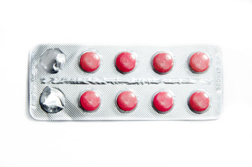 Bright pink, red pills on a white background and in the hands of an adult. Open packaging