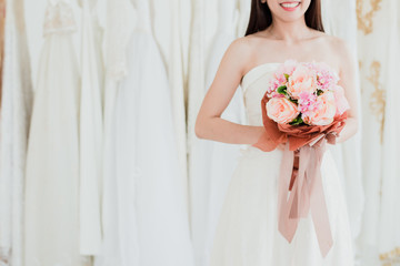 Obraz na płótnie Canvas happy bride in wedding dress with bouquet of roses