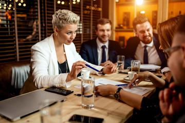 Resolute bright woman with stylish haircut, giving pen to female partner for signing papers. Close up, not looking at camera, business concept