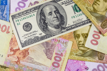 Fototapeta na wymiar American one hundred dollars banknote on the many ukrainian hryvnas