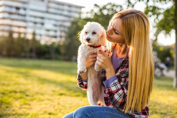 Woman scolding her Maltese dog while they spending time in the park.