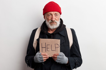 Homeless man holding sign, request for help, seeking help posing at studio over white background