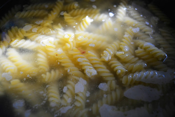 Home cooking, preparing delicious hot dishes. The process of cooking spiral pasta from durum wheat....