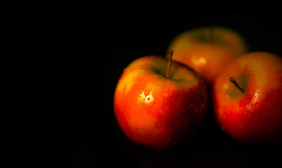 Drei Äpfel mit dunklem Hintergrund und Wassertropfen