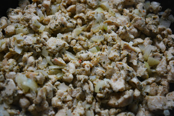 Finely chopped pieces of homemade chicken breast, fried and stewed with onions and sunflower oil. Slices of delicious, juicy chicken lying on a black skillet while frying.