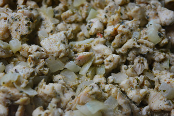 Finely chopped pieces of homemade chicken breast, fried and stewed with onions and sunflower oil. Slices of delicious, juicy chicken lying on a black skillet while frying.