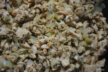 Finely chopped pieces of homemade chicken breast, fried and stewed with onions and sunflower oil. Slices of delicious, juicy chicken lying on a black skillet while frying.