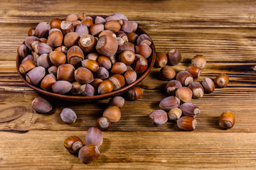 Plate with pile of hazelnuts on a wooden table
