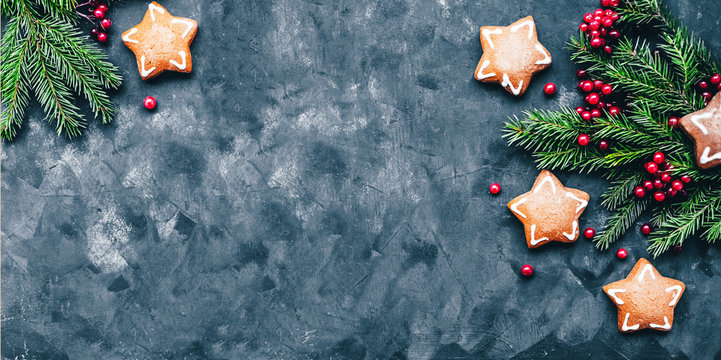 Christmas and New Year background with winter berries, ginger cookies in the form of a star and fir branches in a dark style. Free space and top view.