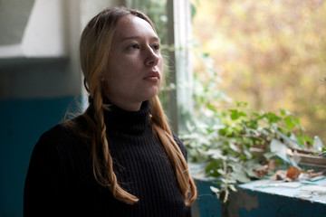 sad girl near the window in an old house