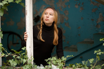 sad girl near the window in an old house
